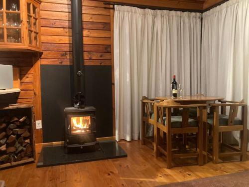 a wood stove in a room with a table and a fireplace at Forest Edge Hideaway -Six on Imbali in George