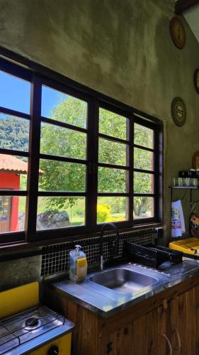 a kitchen with a sink and two windows at Chalé Joanópolis - Rancho da Biruta in Joanópolis