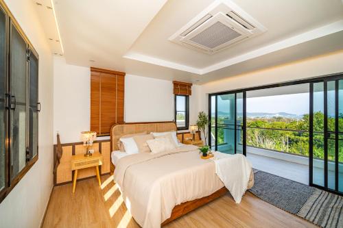 una camera da letto con un letto e una grande finestra di Phu Talae Villa Rawai Beach a Ban Klang