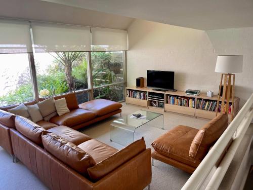 un salon avec des meubles en cuir brun et une télévision dans l'établissement Riversdale Retreat - w. beach & golf course access, à Mollymook