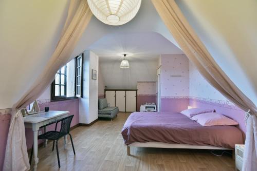 Un dormitorio con una cama y un escritorio y una ventana. en Sylnat - Proche de la mer, en Les Rues