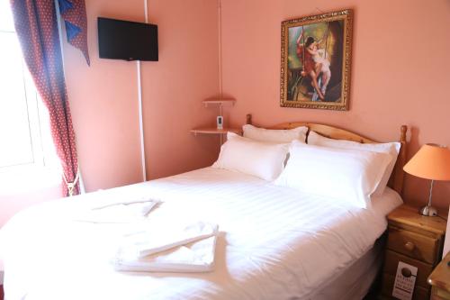 a bedroom with a white bed with a picture on the wall at Twin Lions Hotel in Edinburgh