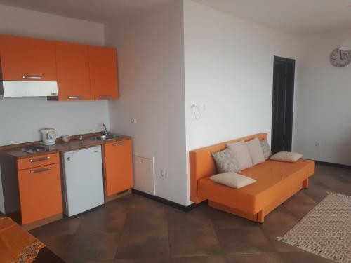 un salon avec un canapé orange et une cuisine dans l'établissement Charmante Wohnung Adriana F, à Dobreć