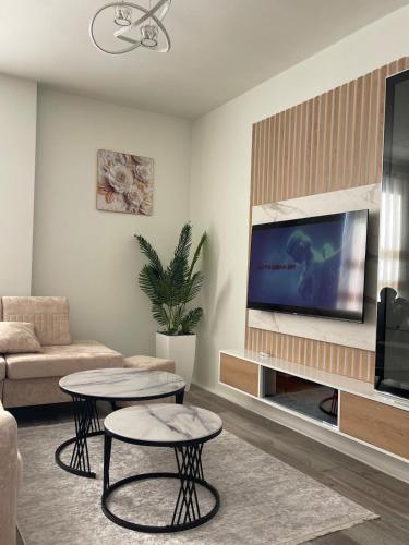 ein Wohnzimmer mit 2 Tischen und einem Flachbild-TV in der Unterkunft Olti in Peshkopi