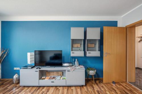 un salon avec une télévision sur un mur bleu dans l'établissement Ferienwohnung Mit Balkon Und Schönem Moselblick, à Schleich