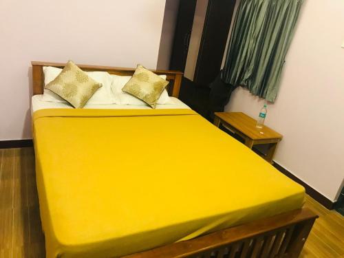 a yellow bed with two pillows on it in a room at Padma residency in Coimbatore