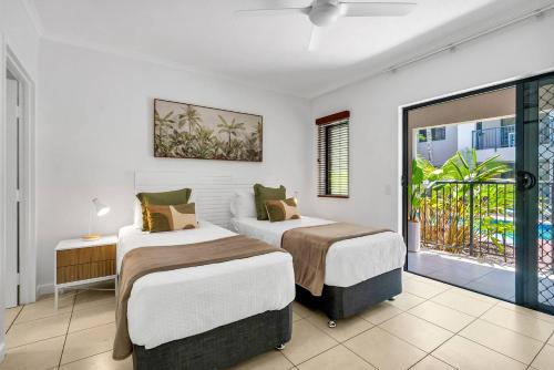 Un dormitorio con dos camas y un balcón. en Laguna Edge - Tranquil Poolside Escape by the Sea, en Trinity Beach