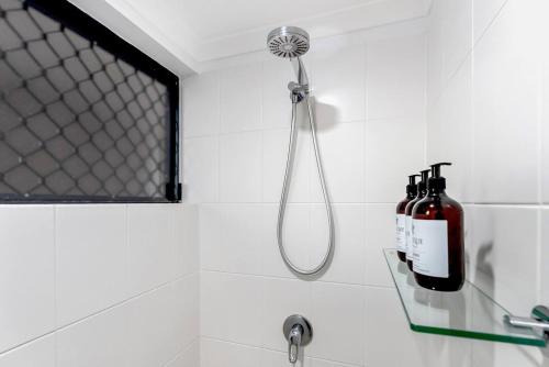 y baño con ducha y 2 botellas de vino. en Laguna Edge - Tranquil Poolside Escape by the Sea, en Trinity Beach