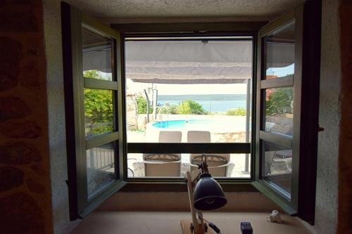 a window with a view of a pool from a house at Ferienhaus In Dobropoljana Mit Privatem Pool in Dobropoljana
