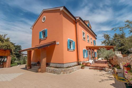 a large orange house with blue shutters on it at Appartement Casper Mit Terrasse, Garten Und Grill in Veli Lošinj