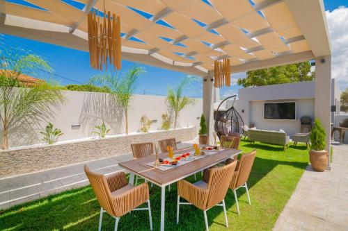 a patio with a table and chairs on the grass at Rua Luxury Villa in Alykes