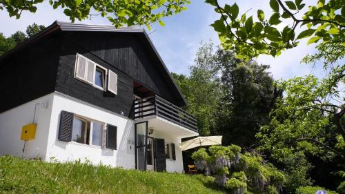 ein weißes und schwarzes Haus mit schwarzem Dach in der Unterkunft Ferienhaus in ruhiger Lage auf einem großen Grundstück, ideal für Naturliebhaber und Ruhesuchende in Tuhelj
