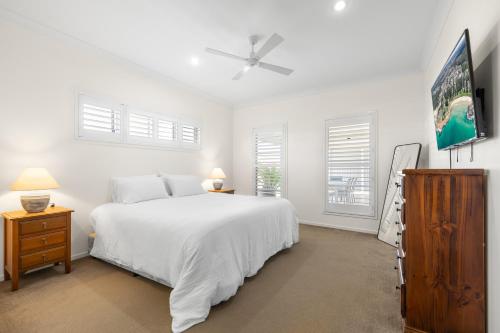 a white bedroom with a bed and a tv at Sea La Vie in Arakoon