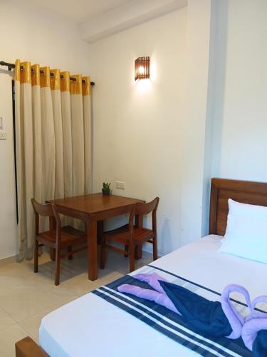 ein Schlafzimmer mit zwei Betten und einem Holztisch in der Unterkunft Zeylon Stay in Weligama