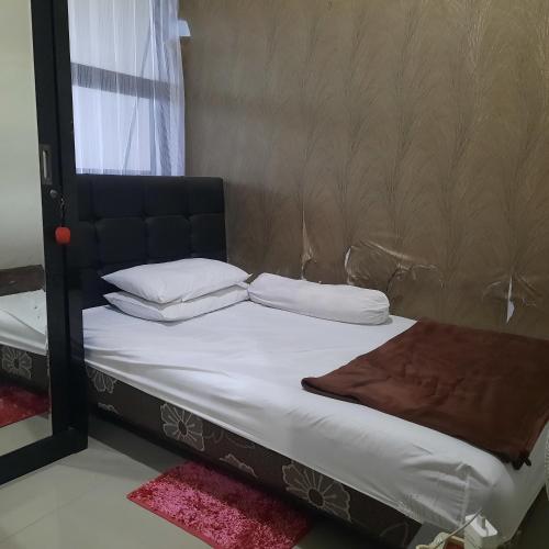 a bed with white sheets and pillows next to a mirror at De Adisucipto Homestay Syariah 2 in Ngadipuro