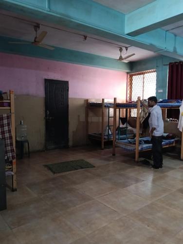 a man standing in a room with bunk beds at V R S Dormitory in Hubli