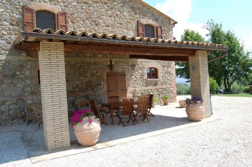 ein Steinhaus mit einer Terrasse mit einem Tisch und Stühlen in der Unterkunft Antikes Landhaus aus Stein mit Pool und einem herrlichen Garten mit Blick auf die Hügellandschaft in Orvieto