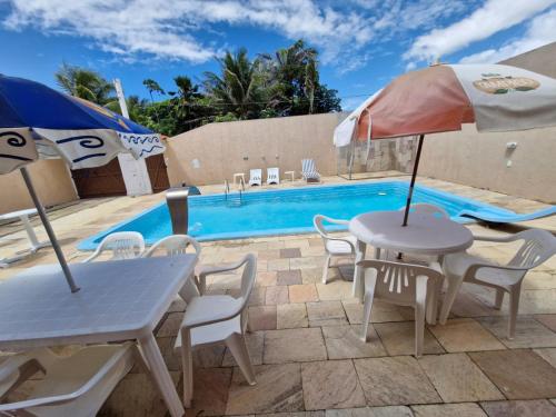 ein Tisch mit Sonnenschirm neben einem Swimmingpool in der Unterkunft Casa de Veraneio com 4 quartos in Barra de São Miguel