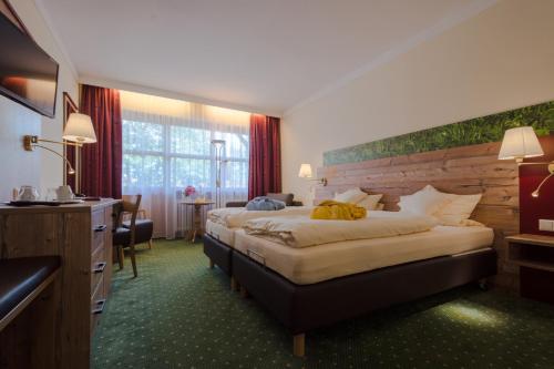 a hotel room with two beds and a desk at Hotel Quellenhof in Bad Birnbach
