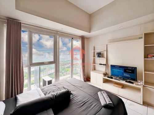 ein Schlafzimmer mit einem großen Bett und einem großen Fenster in der Unterkunft Cozy Casa de Darco Studio Apt BSD W Pool & Gym in Kedeper