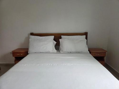 a bed with white sheets and pillows in a room at Passadeira Garden in São Tomé