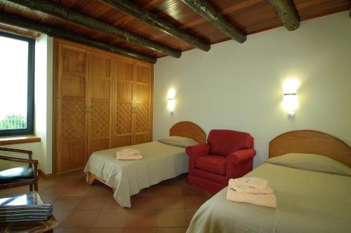 a bedroom with two beds and a red chair at Cottage Ocean View in Porto Moniz