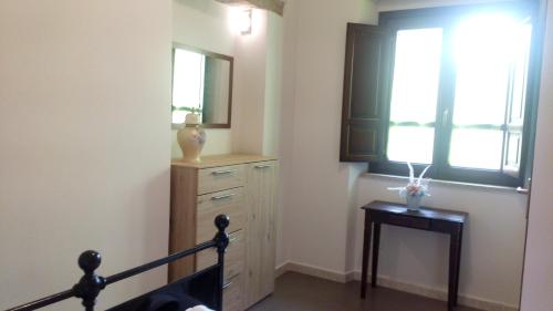 1 dormitorio con tocador, espejo y ventana en Affittacamere Carpe Diem, en Gonnosfanàdiga