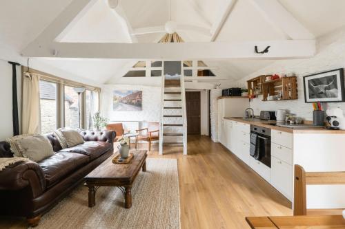 un salon avec un canapé et une table et une cuisine dans l'établissement The Bullpen Cotswolds Farm Stay With Pool, à Lechlade