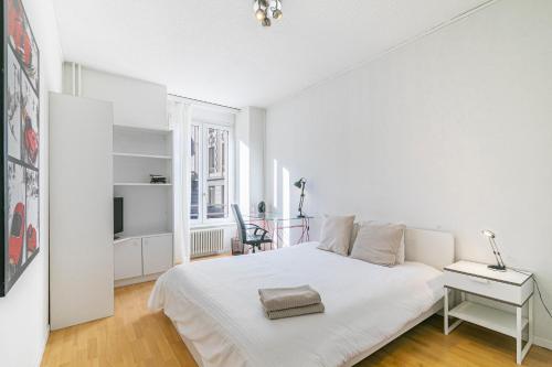 ein weißes Schlafzimmer mit einem weißen Bett und einem Schreibtisch in der Unterkunft Simplon Residence - Central and Self Check In in Lausanne