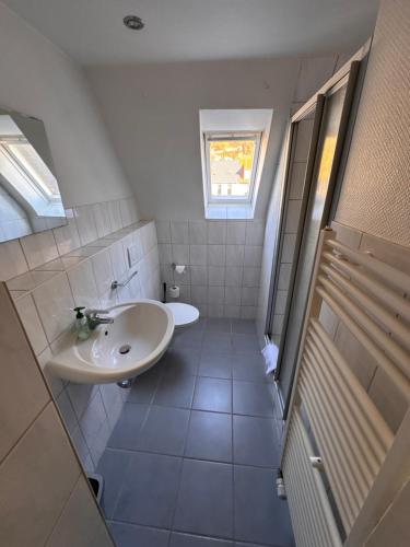 une salle de bain blanche avec un lavabo et une fenêtre dans l'établissement Gasthaus & Pension Grüner Baum Eberbach, à Eberbach