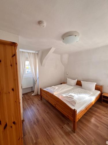 - une chambre avec un grand lit en bois et des draps blancs dans l'établissement Gasthaus & Pension Grüner Baum Eberbach, à Eberbach