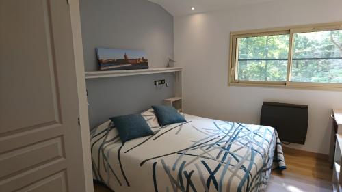 une chambre avec un lit avec des oreillers bleus et une fenêtre dans l'établissement Le Pigeonnier De La Villa Lamoure, à Villaudric