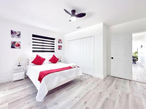 a white bedroom with a large white bed with red pillows at Miami Lux Retreat - Free Parking - Near Brickell in Miami