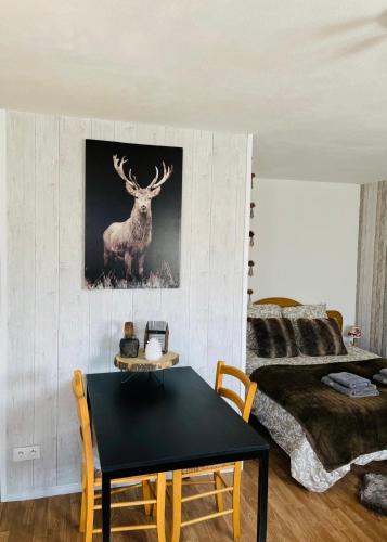 a bedroom with a table and a deer picture on the wall at Le refuge du Cerf in Allemont