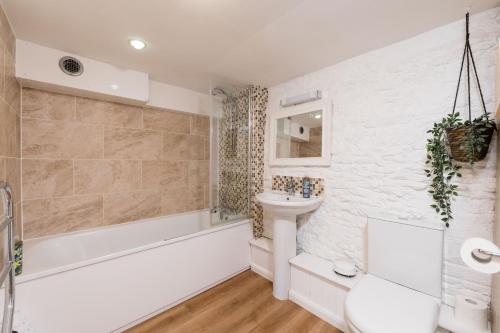 une salle de bain avec une baignoire, un lavabo et des toilettes dans l'établissement The Dairy Cotswolds Cottage Farm With Pool, à Lechlade