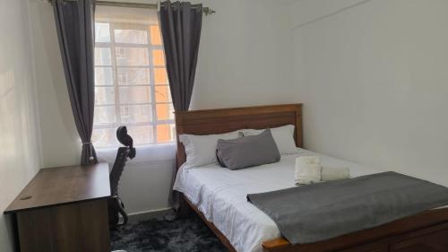 Un dormitorio con una cama y un escritorio y una ventana. en Cynergy 1b Apartment, Muthiga , Waiyaki Way, en Nairobi