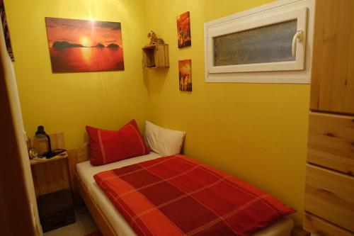 - une petite chambre avec un lit et des oreillers rouges dans l'établissement Zoe, à Osterbrücken