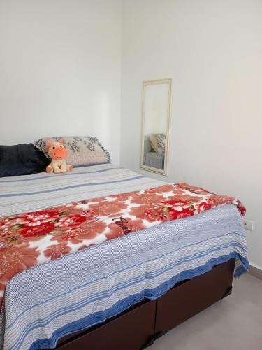 a bedroom with a bed with a teddy bear on it at Bem praiana in Praia Grande