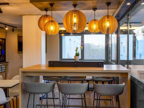 une cuisine avec un bar avec des chaises et des lumières dans l'établissement B&B HOTEL Koblenz-Nord, à Mülheim-Kärlich