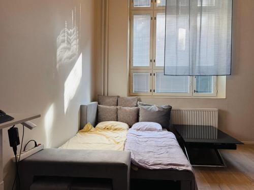 a bed in a room with a couch and a window at Double Sofa Bed in a Stunningly Tall Shared Studio in Helsinki