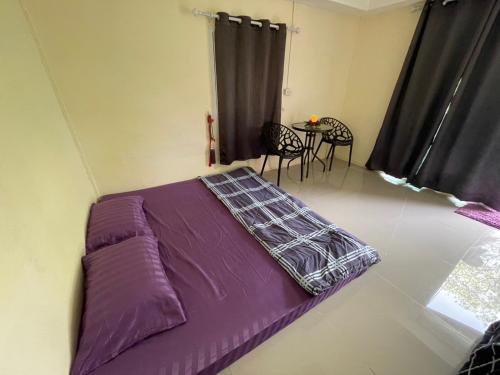 a purple bed in a room with a table and chairs at บ้านมาดาม เขาใหญ่ in Ban Chek