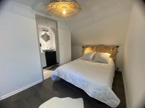 een slaapkamer met een wit bed en een spiegel bij La Petite Maison in Moyrazès
