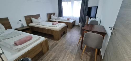 a room with two beds and a desk and a television at Vándor Szálló in Kecskemét