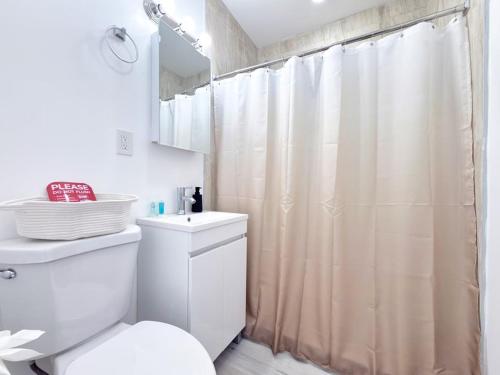 a bathroom with a white toilet and a shower curtain at Lux Miami Escape - Near Brickell- Free Parking in Miami