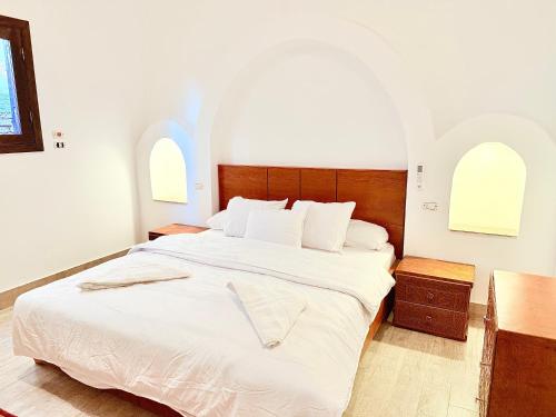 a bedroom with a bed with white sheets and two windows at Saray El Omda - Wellness & Retreat Village in Luxor