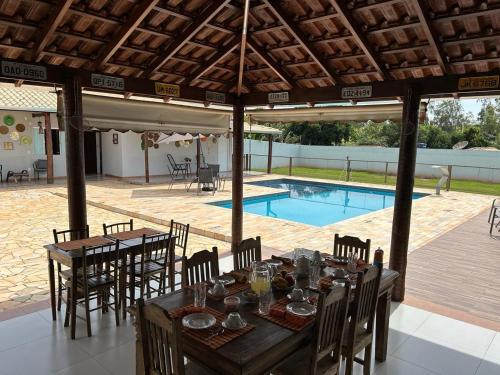 Pousada Vale Canastra في ساو جواو باتيستا دو غلوريا: طاولة طعام وكراسي تحت جناح مع مسبح