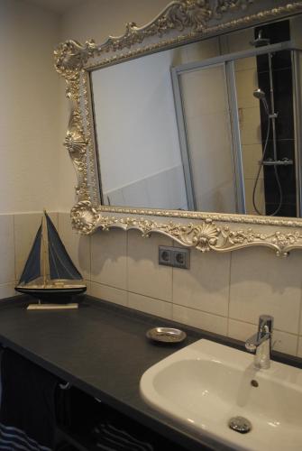 a bathroom with a sink and a mirror with a boat on it at Ferienwohnungen Meerwiefke in Leer