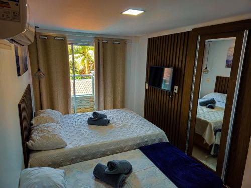 a hotel room with two beds and a mirror at Makambira Residence no Centro de Porto de Galinhas in Porto De Galinhas