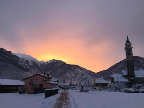 una ciudad con una torre de reloj en la nieve en Rustico Di Vacanza Nel Nucleo Di Moghegno, en Moghegno