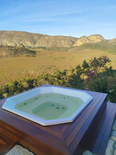 a jacuzzi tub on a deck with mountains in the background at Vale do Elefante - Casa com Jacuzzi e Cachoeira in Santana do Riacho